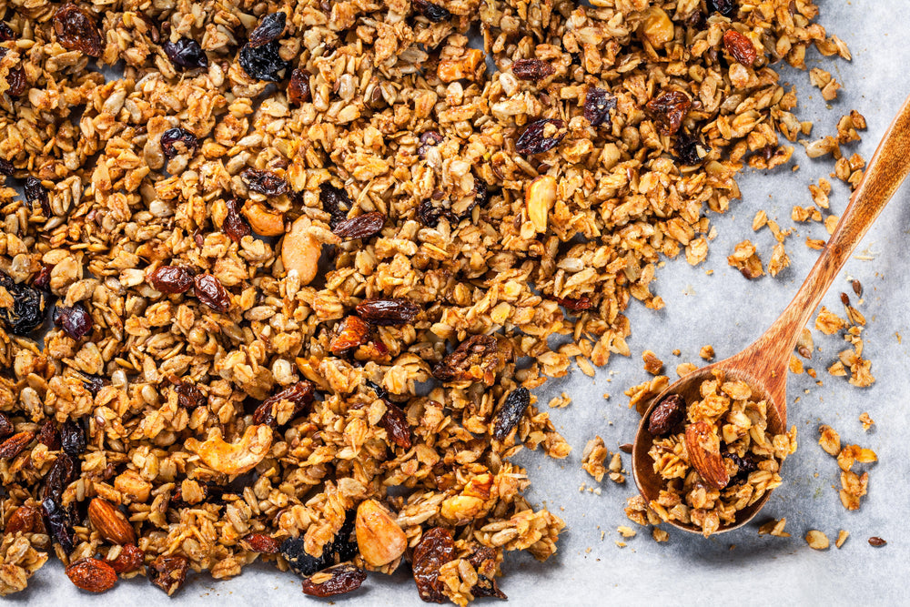 Knuspriges Granola mit Nüssen und Haferflocken auf Backpapier.