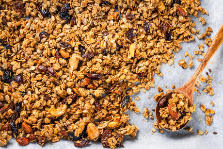 Gebakken granola met noten en rozijnen op bakplaat.