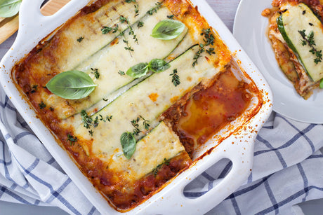 Courgette-lasagne met kaas en verse basilicum in ovenschaal.