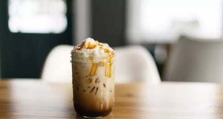 Iced Pumpkin Spice Latte mit Protein, Eiswürfeln, Sahne und Karamellsauce im Glas