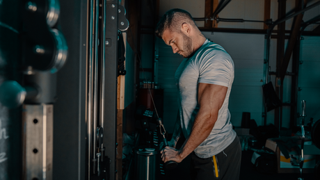 Uomo allena tricipiti con cavo in palestra.