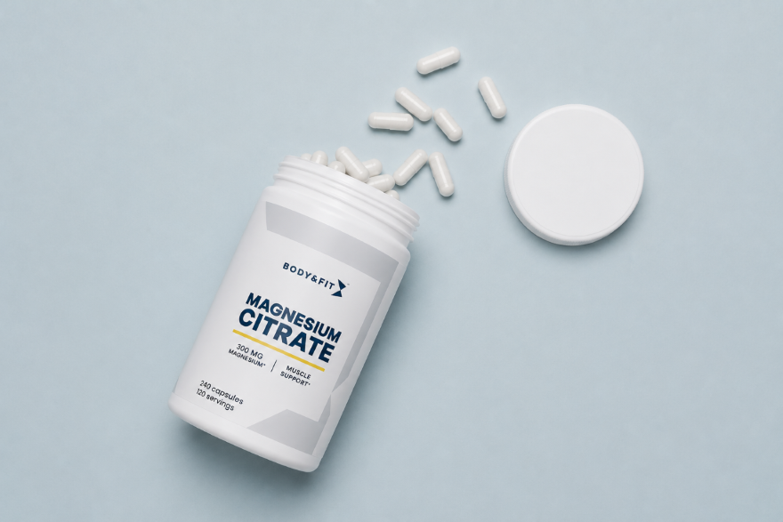 Pot de complément alimentaire Magnésium Citrate Body & Fit ouvert avec des capsules blanches sur fond bleu clair