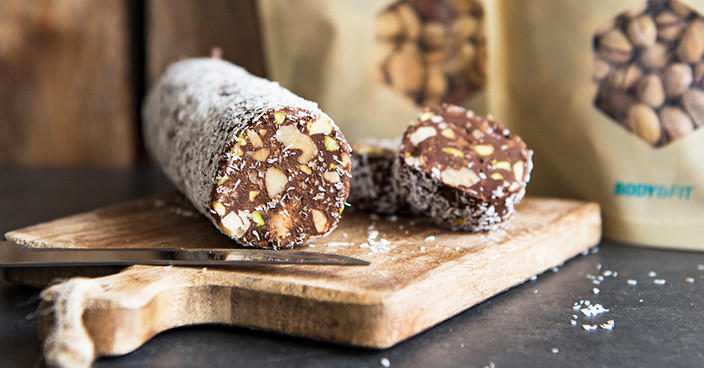 Chocoladesalami met noten op houten snijplank.