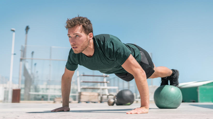 Man doet push-up met handen op fitnessbal.