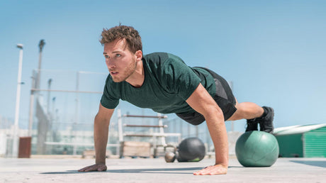 Man doet push-up met handen op fitnessbal.