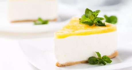 Punt citroen cheesecake met munt op wit bord.