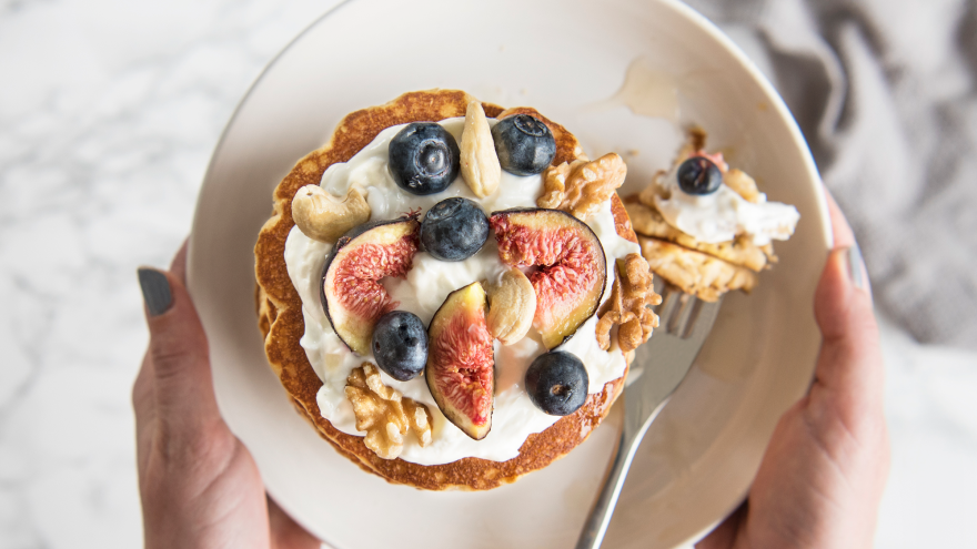 Gesunder Pancake mit Quark, Feigen, Blaubeeren und Nüssen auf Teller.