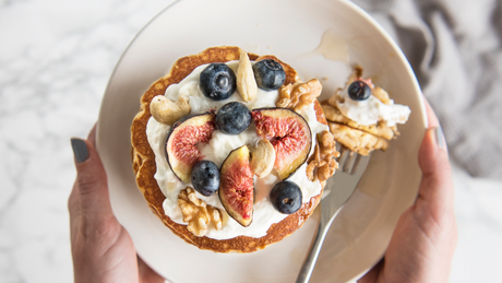 Gesunder Pancake mit Quark, Feigen, Blaubeeren und Nüssen auf Teller.