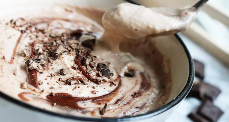 Chocolate protein mousse with swirled sauce and dark chocolate pieces.