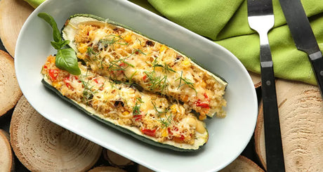 Gevulde courgette met kaas, quinoa en groenten in ovenschaal.