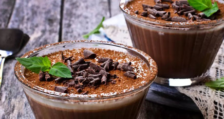 Glass cups of chocolate pudding with mint topping.