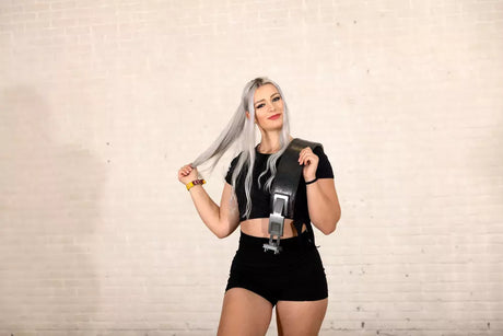 Woman in fitness gear holding lifting belt and smiling.