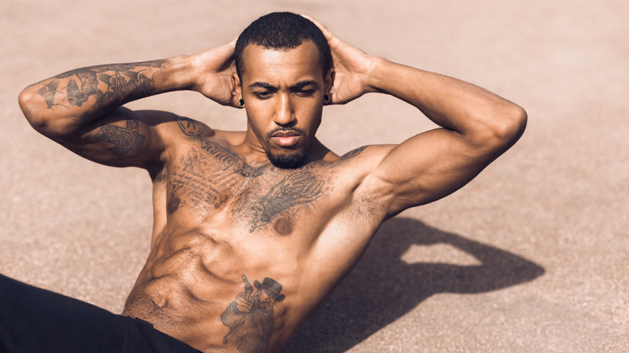 Fit man performing sit-ups on pavement.