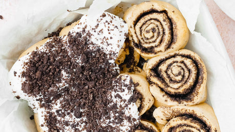 Kaneelbroodjes met Oreo topping en glazuur in bakvorm.