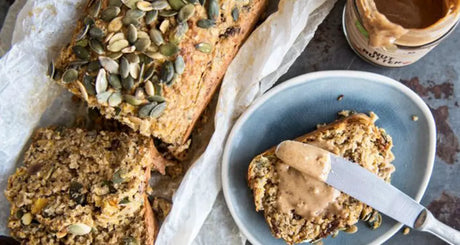Plak bananenbrood met pindakaas en pompoenpitten.