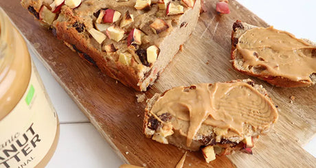 Appelrozijnenbrood met pindakaas op houten plank.