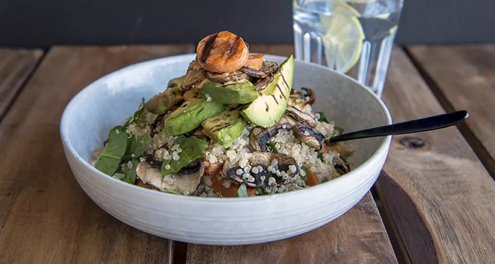 Healthy quinoa bowl topped with avocado and mushrooms.
