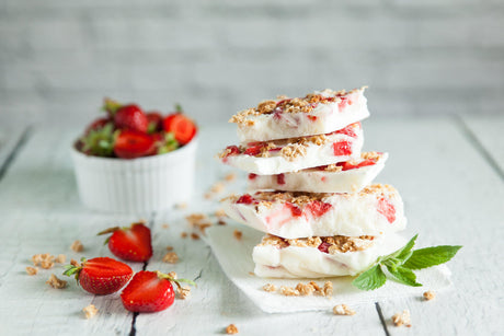 Gefrorene Joghurtriegel mit Erdbeeren und Knuspergranola gestapelt.